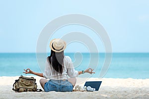 Lifestyle freelance woman relax and sitting meditation on the beach.Â 